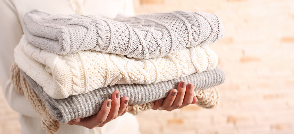 PRALKA SHARP ES-HFM6102WD Stos starannie złożonych, grubych swetrów w jasnych kolorach. Zdjęcie symbolizuje delikatne pranie odzieży wełnianej pranie wełny delikatne tkaniny łagodny cykl ochrona ubrań pielęgnacja materiałów