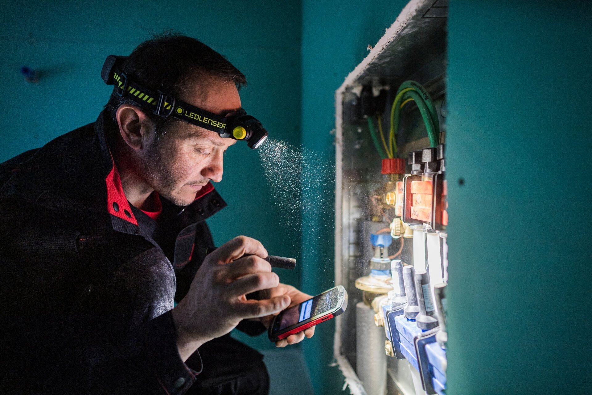 Latarka LEDLENSER H5R Work, światło, praca, oświetlenie, źródło, mężcyzna podświetla okablowanie w ścianie latarką