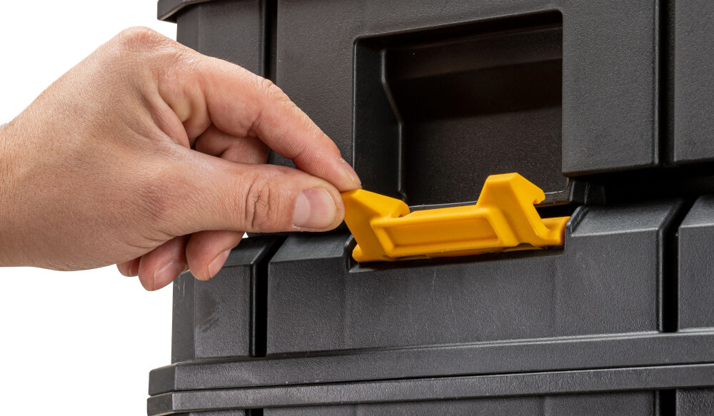 Skrzynka narzędziowa DEWALT DWST83345-1 białe tło osoba trzyma zawias w dłoni obudowa z tworzywa sztucznego odporna na uszkodzenia mechaniczne i działanie czynników zewnętrznych metalowe zatrzaski i metalowe zawiasy udźwig do 30 kg