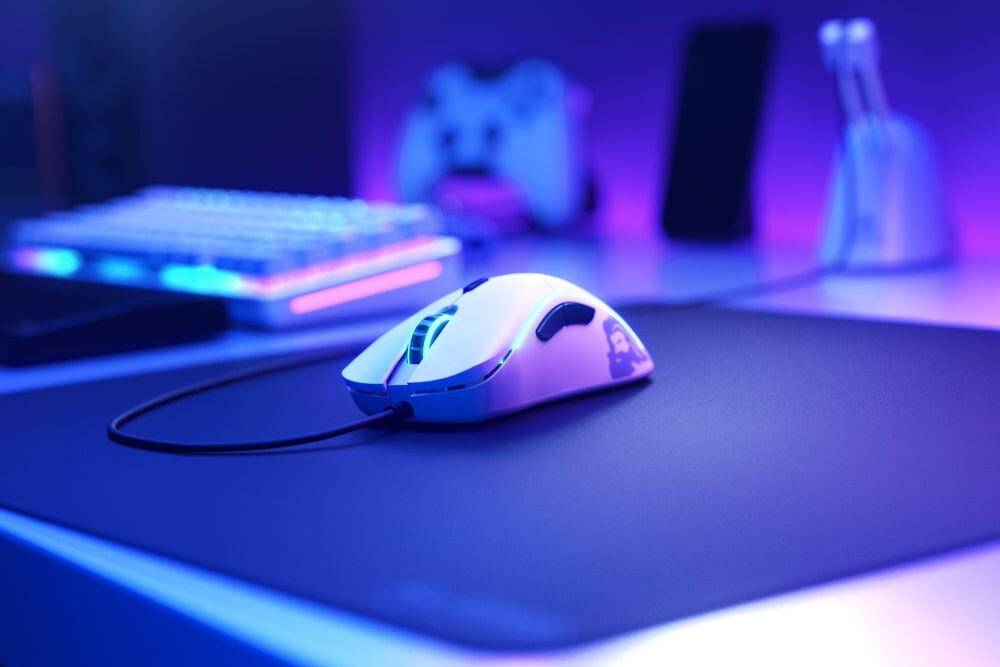 Mysz GLORIOUS PC Gaming Race Model D- Matte White na biurku podświetlonym w niebieskiej kolorystyce