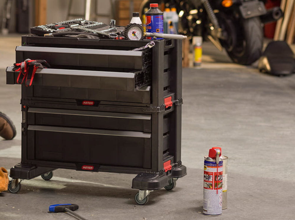 Regał narzędziowy KETER Tool Chest 237007 garaż regał wypełniony narzędziami i różnymi rzeczami stoi na podłodze w tle motor pojemność do 33,4 l wymiary 56,2 x 28,9 x 50,2 cm optymalne rozplanowanie szuflad i pojemników szybki dostęp do narzędzi