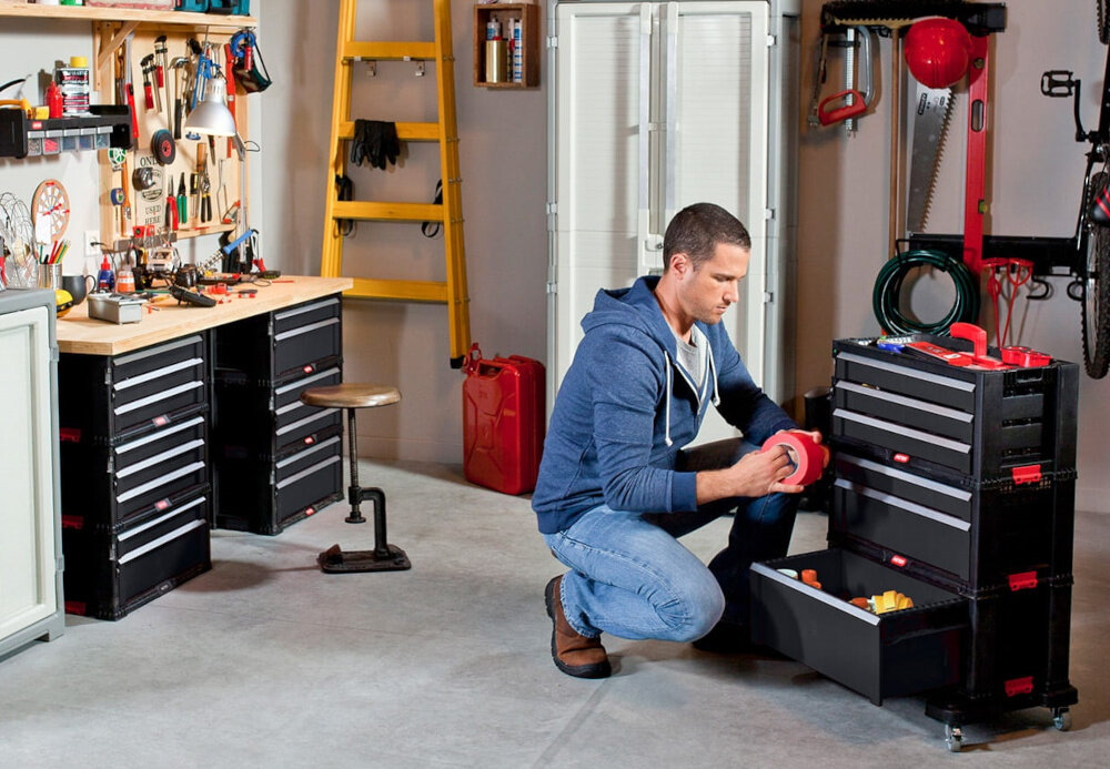 Regał 3 szuflady KETER Tool Chest warsztat garaż osoba klęczy obok skrzynek narzędziowych organizacja pracy porządek segregacja