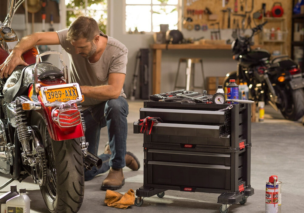 Regał 3 szuflady KETER Tool Chest warsztat garaż osoba klęczy obok motoru naprawia motor obok skrzynki narzędziowe Trzy głębokie szuflady o łącznej pojemności 17,1 l wewnętrzne wymiary 43,5 x 23 x 5 cm (wszystkie szuflady) praca staje się bardziej płynna i uporządkowana z trwałego tworzywa odporność na uszkodzenia mechaniczne obciążenie do 30 kg