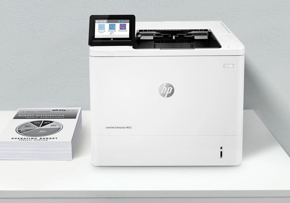 Drukarka HP LaserJet Enterprise M612dn Automatyczny druk dwustronny Biała drukarka z dużym ekranem dotykowym stoi na biurku obok stosu wydrukowanych dokumentów, opis