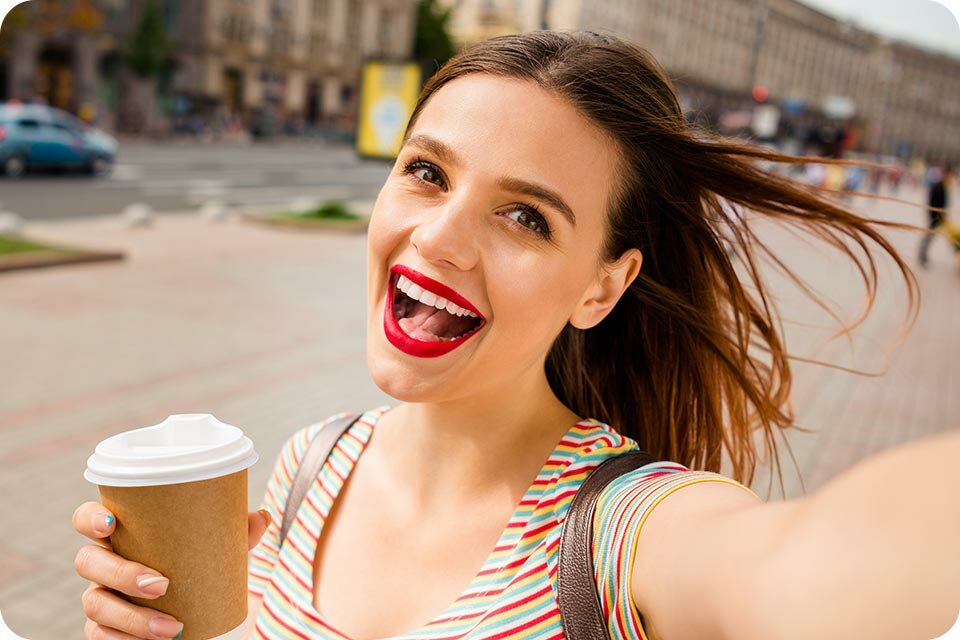 Uśmiechnięta młoda kobieta trzymająca kubek z kawą Uśmiechnięta młoda kobieta trzymająca kubek z kawą