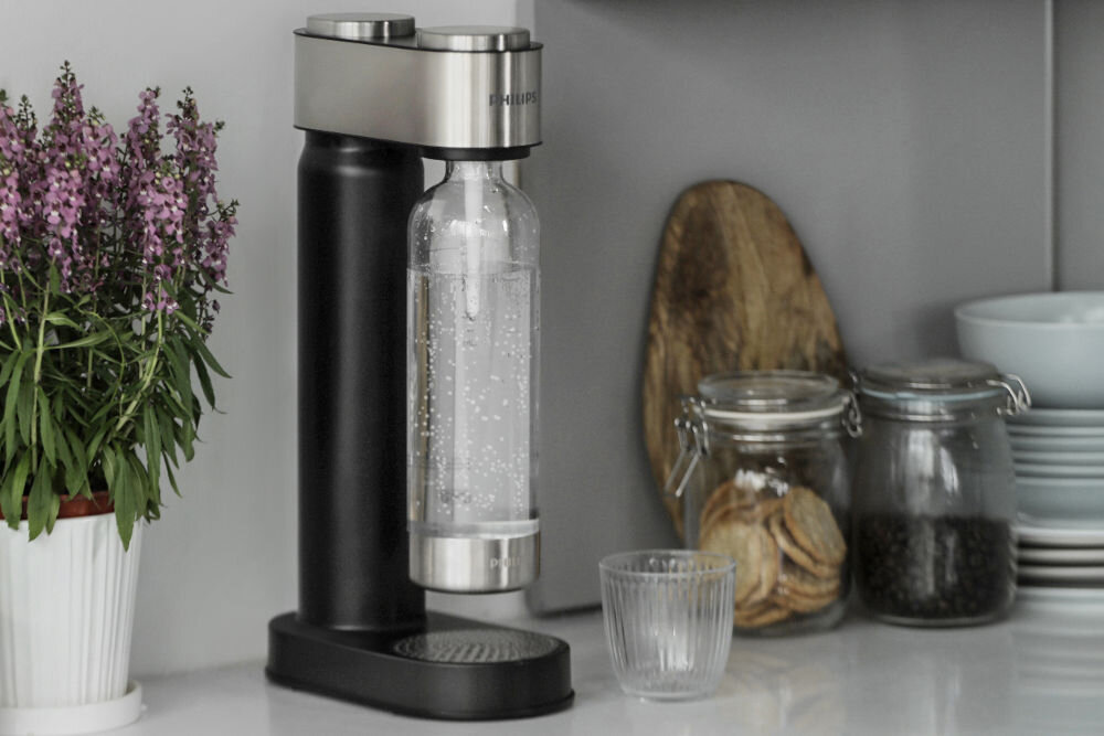 Saturator PHILIPS ADD4902BK/10 GoZero Elegancki saturator Philips Soda Maker w kolorze czarnym ze stalowymi wykończeniami, stojący na jasnym blacie w nowoczesnej kuchni.