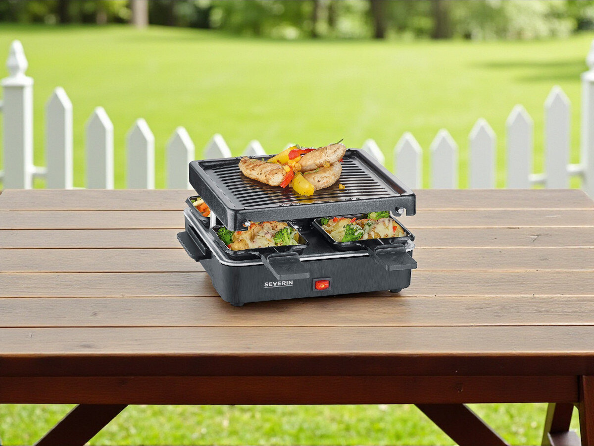 Grill elektryczny SEVERIN RG2370, grillowanie, gotowanie, ogród, kuchnia, grill stoi na blacie stołu drewnianego w ogrodzie, w tle płotek ogrodowy