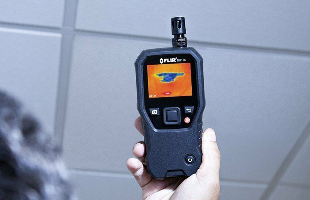 Higrometr termowizyjny FLIR MR176 IGM 80x60px + czujnik + sonda stykowa osoba trzyma urządzenie w dłoni technologia funkcja kamery termowizyjnej z pomiarami wilgotności lokalizowanie problemów z wilgocią technologia IGM™ Infrared Guided Measurement diagnozowanie identyfikowanie problemów