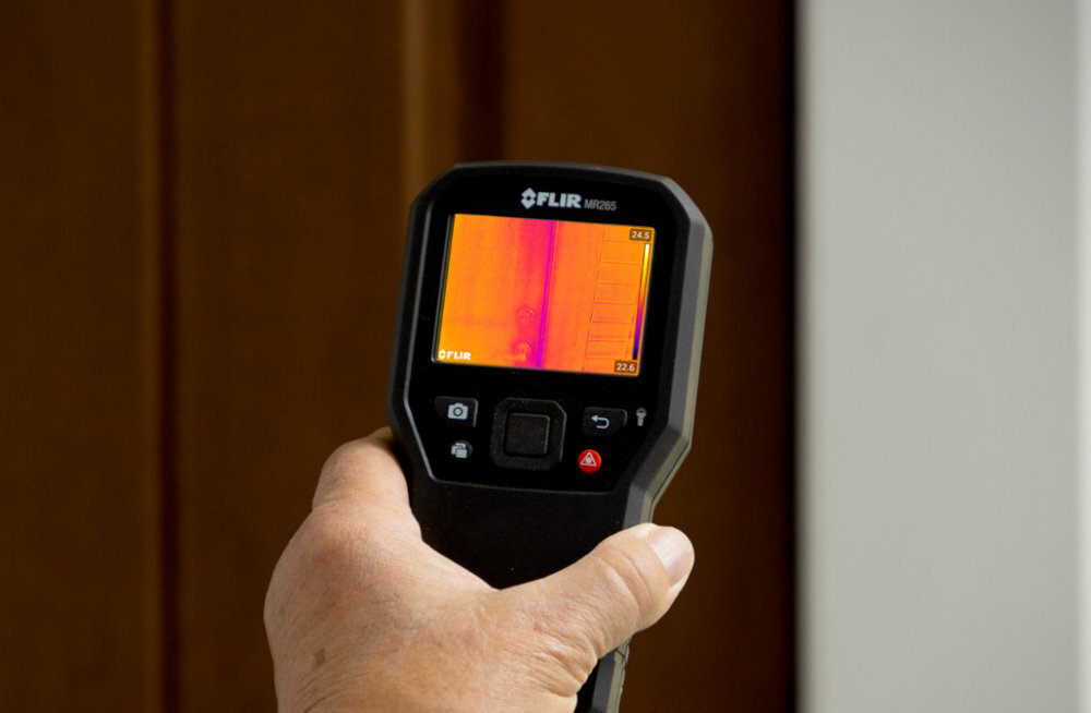 FLIR MR277 FLIR MR277 kamera termowizyjna pomiaru wilgotności izolacją, nieszczelności czy zawilgocenia materiałów zakresie od 0 do 100°C ekran LCD 2.8 cala - kamera na tle drzwi drewnianych