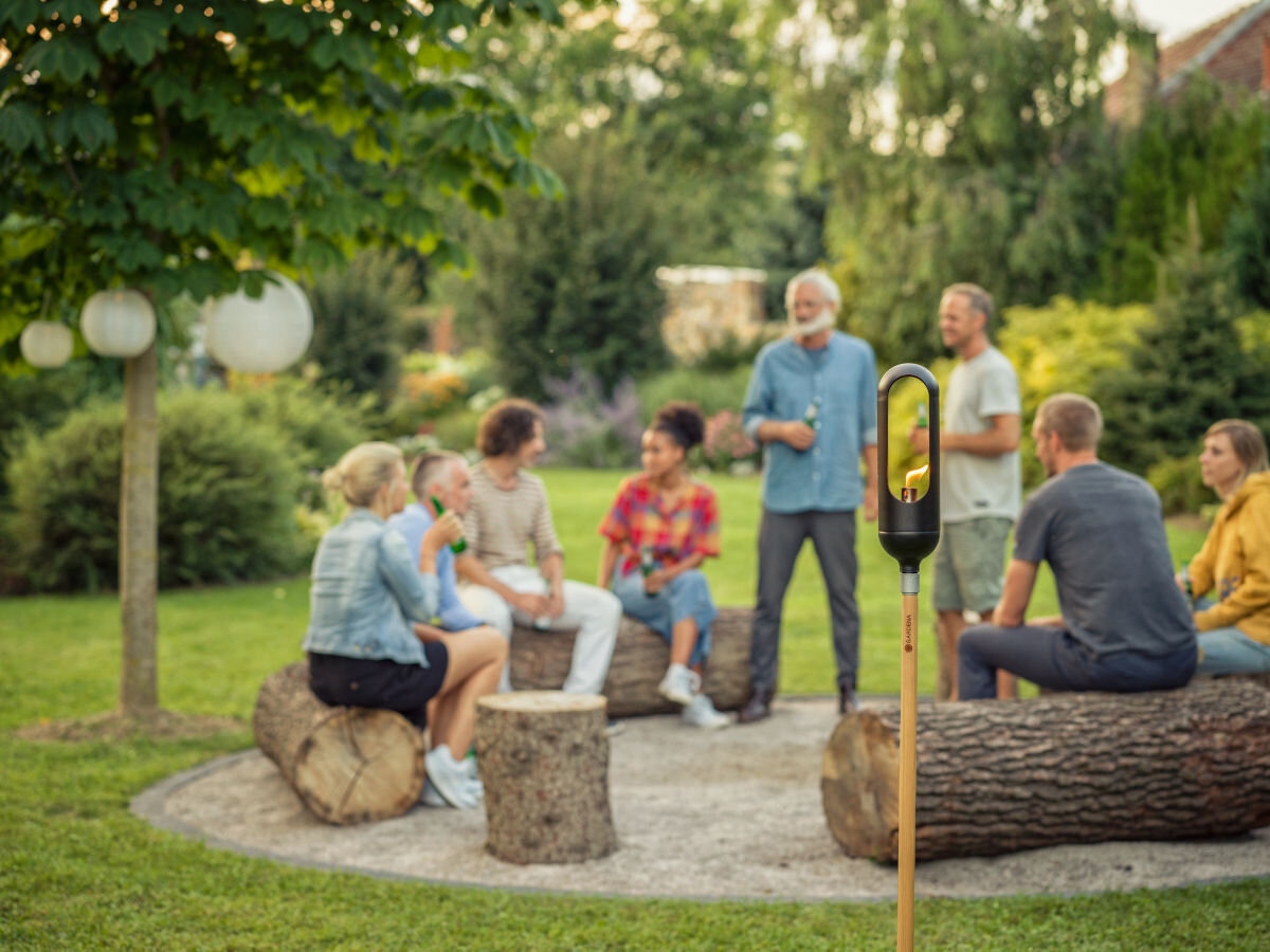 Pochodnia GARDENA Clickup 11360-20, click up, kompatybilna, regulacja, dopasowanie, w tle ogród i rodzinne spotkanie, na pierwszym planie postawiona pochodnia