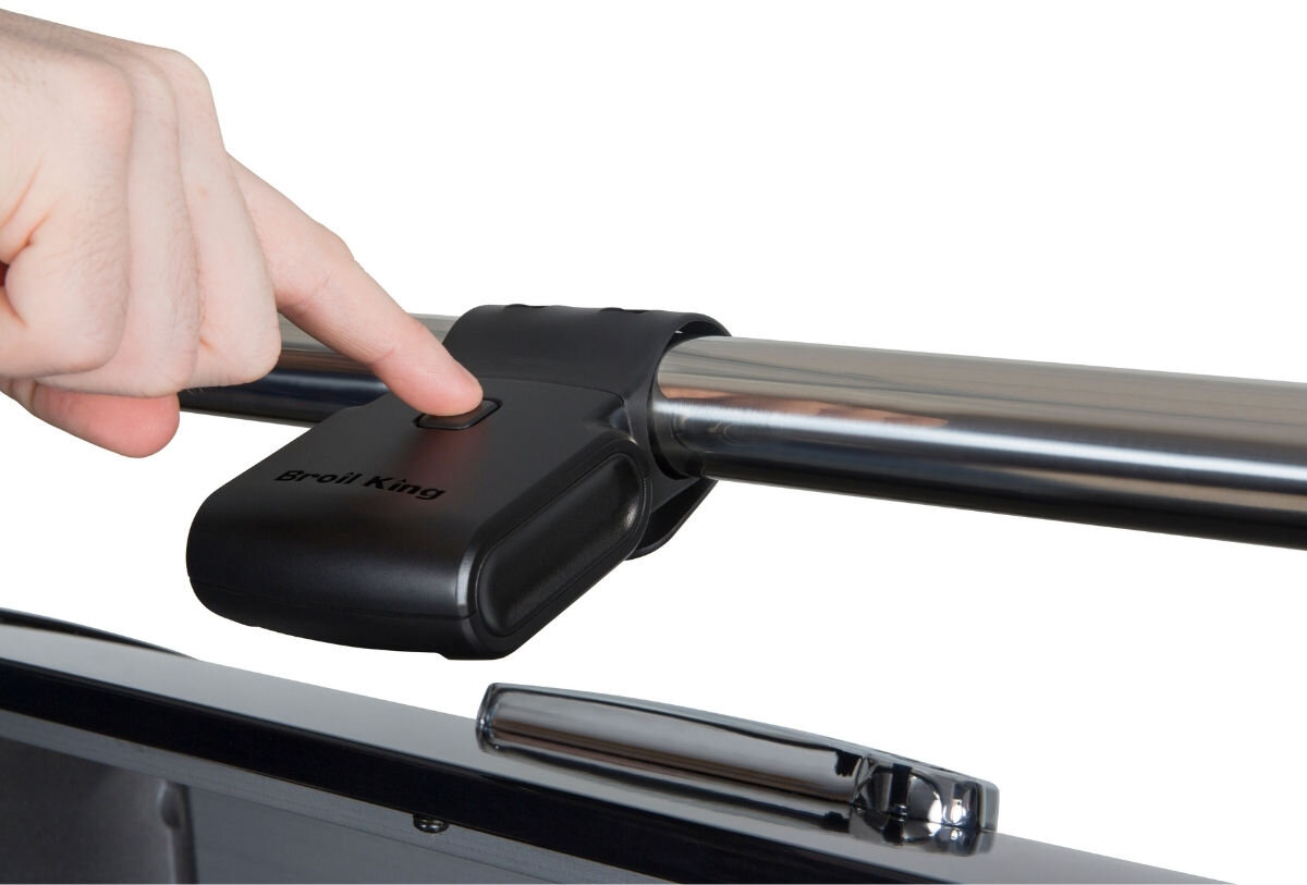 Latarka do rusztu BROIL KING 60934, przycisk, włącznik, obsługa, światło, Palec wskazuje przycisk włączania na czarnej lampie LED Broil King Good-King zamocowanej na stalowej rurze grilla.