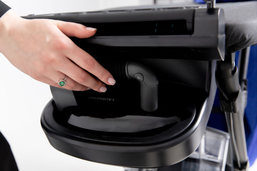 System do prasowania LAURASTAR Smart U osoba trzyma czarną obudowę deski przycisk jasne tło Jedna kropla wody subtelna Sucha Para DMS (Dry Microfine Steam) aż 1600-krotnie z zawrotną prędkością 15 razy szybciej wyjątkowa para wytrzymały denim delikatna satyna dokładne odświeżenie odzyskanie naturalnej struktury prosto z metki