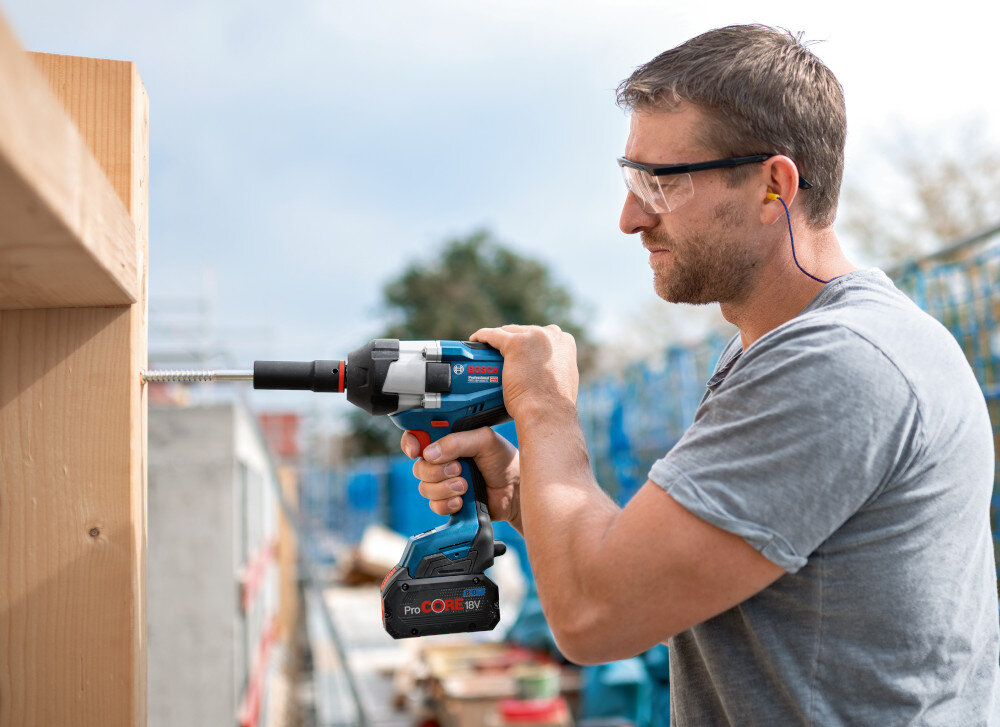 Klucz udarowy BOSCH Professional GDS 18V-1050 H 06019J8502 osoba pracuje narzędziem w drewnie zasilanie akumulatorowe pełna swoboda pracy dwa akumulatory z serii ProCore o pojemności 8.0 Ah ładowarka szybkie ładowanie minimalizuje przestoje