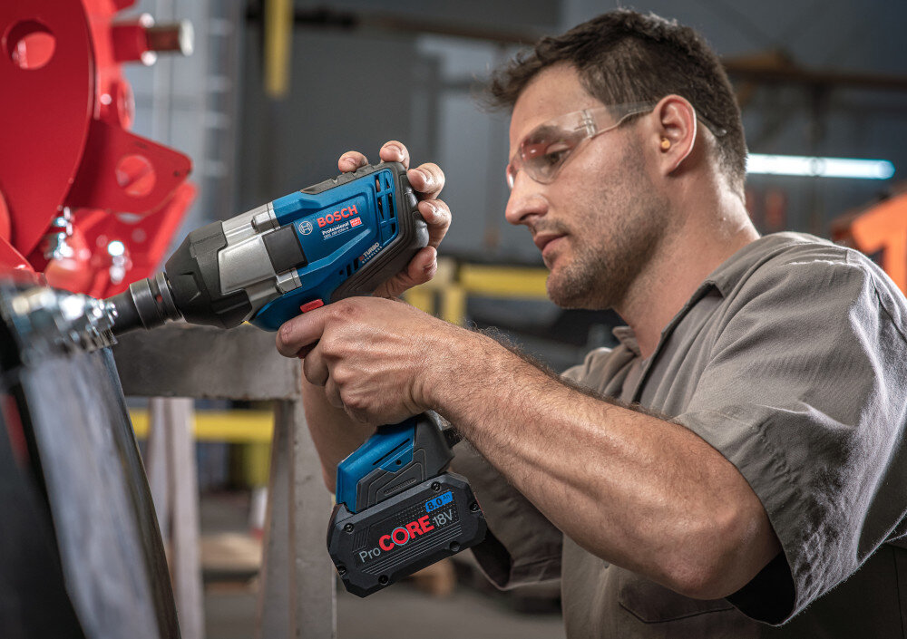 Klucz udarowy BOSCH Professional GDS 18V-1050 H 06019J8502 osoba używa narzędzia obudowa odporna na uszkodzenia ergonomiczny kształt rękojeści wygodne użytkowanie antypoślizgowa powłoka bezpieczna praca waga 2,9 kg