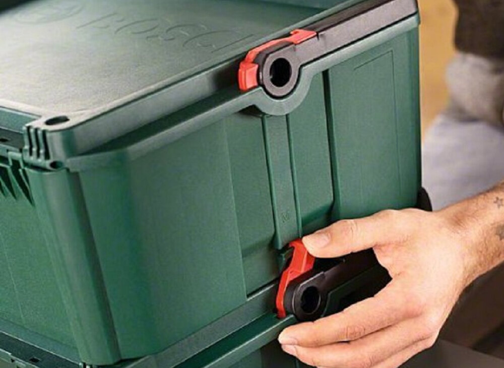 Skrzynka na narzędzia BOSCH 1600A016CT zbliżenie na boczne uchwyty osoba trzyma uchwyt w dłoni część systemu SystemBox łączenie kilku walizek w jedną stabilną konstrukcję modułowa budowa mobilność zorganizowany system boczne uchwyty