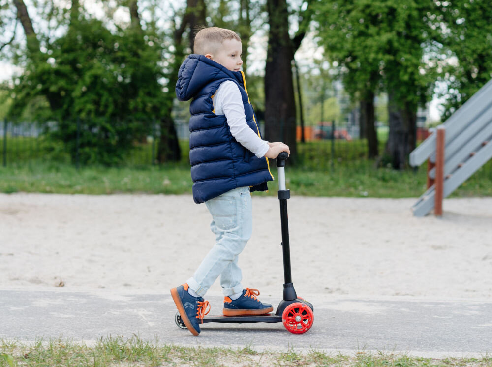 Hulajnoga dla dzieci FERRARI FXK5 Czarny chłopiec jedzie na hulajnodze bezpieczenstwo stabilna jazda tylny blotnik funkcja hamulca noznego bezpieczenstwo na drodze latwa kontrola pojazdu dostosowanie predkosci