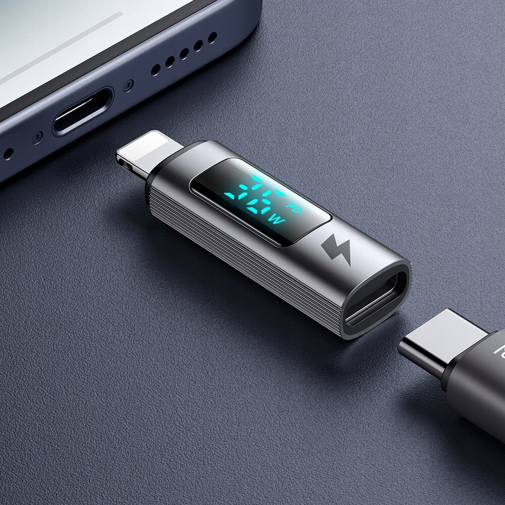 Na obrazie widoczny jest adapter USB-C do Lightning z wyświetlaczem pokazującym \'21.1W\'. Obok znajduje się fragment smartfona z portem Lightning.