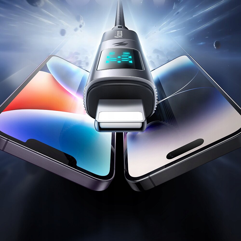 Na obrazie widoczny jest adapter USB-C do Lightning z wyświetlaczem, na którym widać cyfry. W tle znajdują się dwa smartfony z kolorowymi ekranami.
