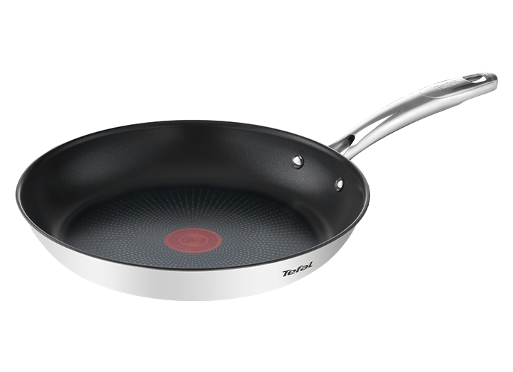 Na obrazie widoczna jest stalowa patelnia z czarnym wnętrzem i czerwonym okręgiem na środku. Na boku patelni znajduje się logo \'Tefal\'.