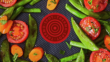 Zbliżenie na wskaźnik patelni Tefal Duetto G7333855, wokół niego warzywa.