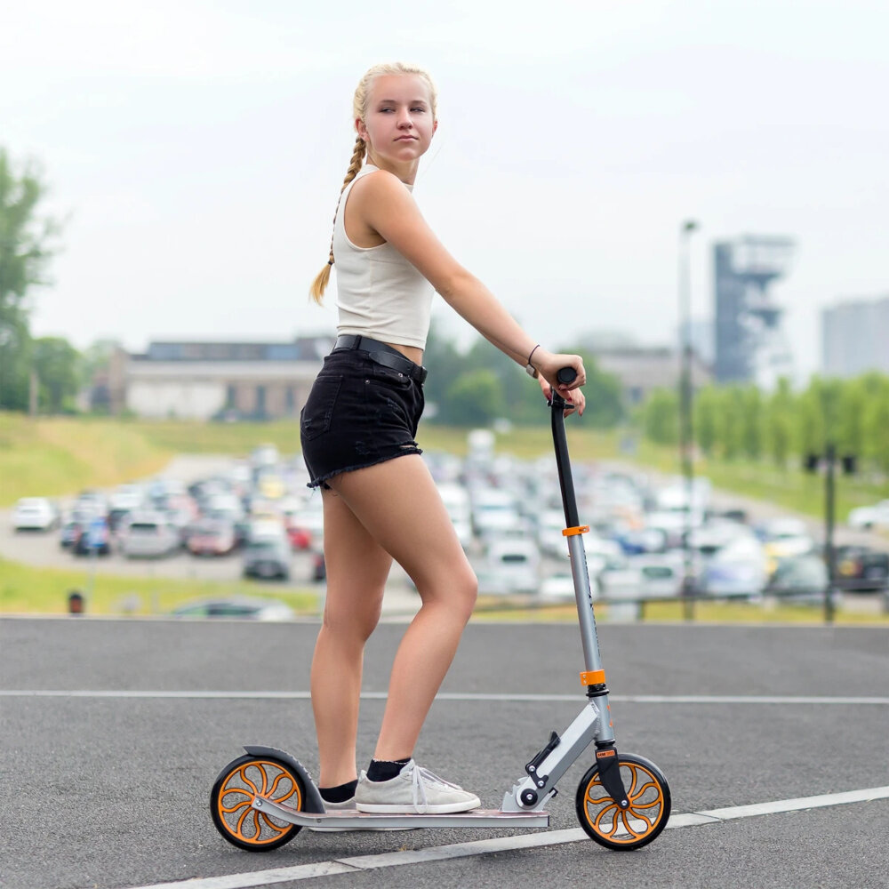 Hulajnoga NILS EXTREME HM203 Czarno-srebrny dziewczyna opiera stopę na podeście niepowtarzalny design funkcjonalność niezapomnianą frajdę z jazdy ergonomiczna konstrukca solidne materiały dla dzieci młodzieży dorosłych od 7 roku życia rozwój koordynacji ruchowej równowagi kondycji dziecka uniwersalny design dla dziewczynek i chłopców
