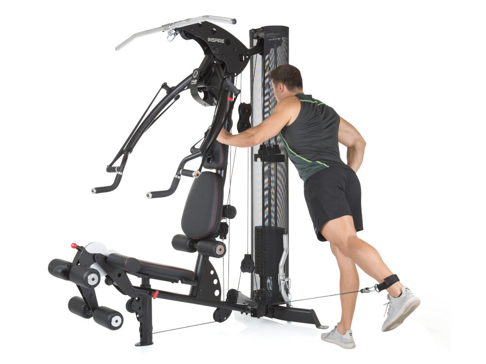 Atlas FINNLO Maximum Inspire M2 urządzenie na białym tle osoba stoi ćwicząc profesjonalna przystawka do ćwiczenia mięśni nóg moduł wyprostu i zginania nóg stacja do ćwiczeń nóg