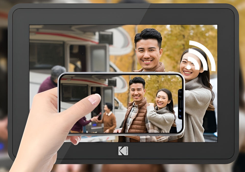 Ramka cyfrowa KODAK RCF-106 Biały prezentacja ramki ze zdjęciem przed nią ręka trzymająca telefon znak Wi-Fi aplikacja Kodak Photo Frame przesyłanie zdjęć i filmów z dowolnego miejsca na świecie