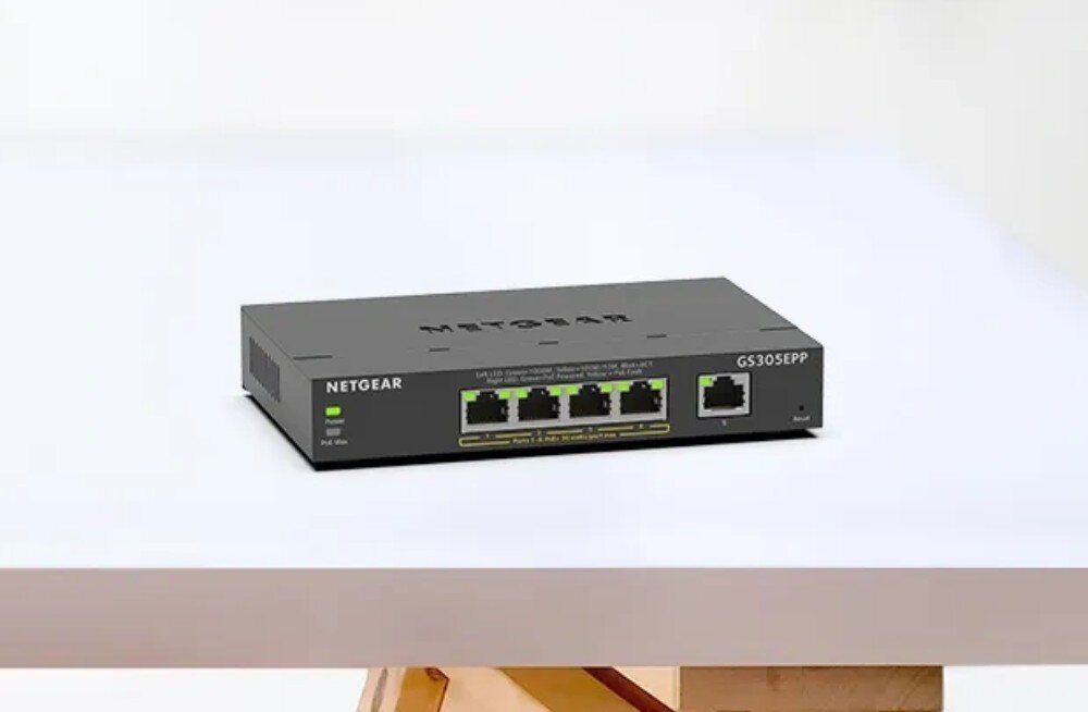 Switch NETGEAR GS305EPP-100PES Przełącznik sieciowy umieszczony centralnie na białej, gładkiej powierzchni stołu, porty, prędkość, zasilanie PoE, przepustowość