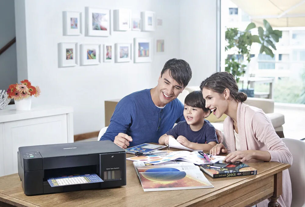 Urządzenie wielofunkcyjne BROTHER DCP-T420W Druk w kolorze, Wi-Fi prezentacja urządzenia w jasnym pokoju na stole rodzina siedząca przy nim