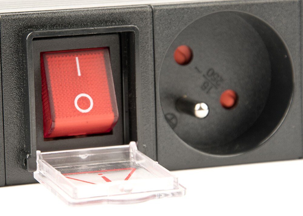 Listwa ENERGENIE EG-PDU-014-FC14 Zbliżenie na czerwony przełącznik zasilania z podniesioną przezroczystą osłoną, na której znajduje się czerwony trójkątny symbol ostrzegawczy, umieszczony obok czarnego gniazda