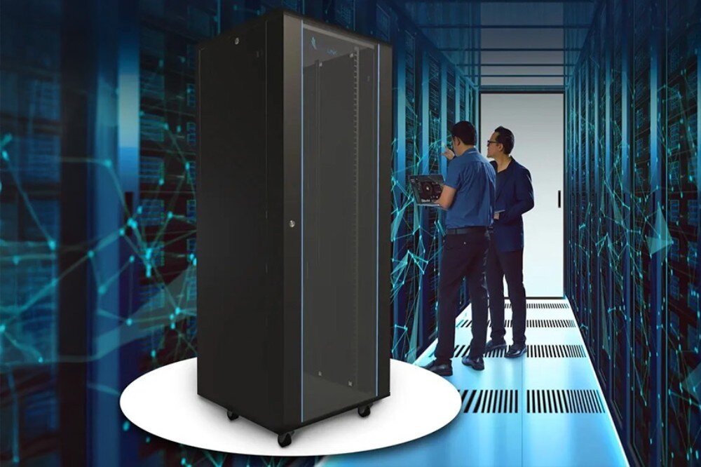 Szafa RACK EXTRALINK 19 42U EX.8628 600 x 800 mm Czarna szafa rackowa stoi na jasnym okrągłym tle w korytarzu serwerowni, obok dwóch osób pracujących przy urządzeniach sieciowych