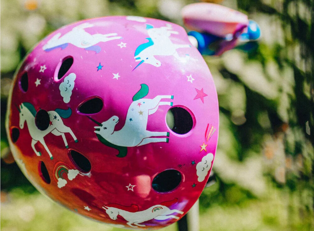 Kask HORNIT Unicorn Fioletowy dla Dzieci (rozmiar M) park drzewa kask wisi na kierownicy hulajnogi ochrona głowy dziecka bezpieczeństwo w sytuacjach niespodziewanych lekka budowa ciekawy wzór wygodne wnętrze komfort i spokój rodziców