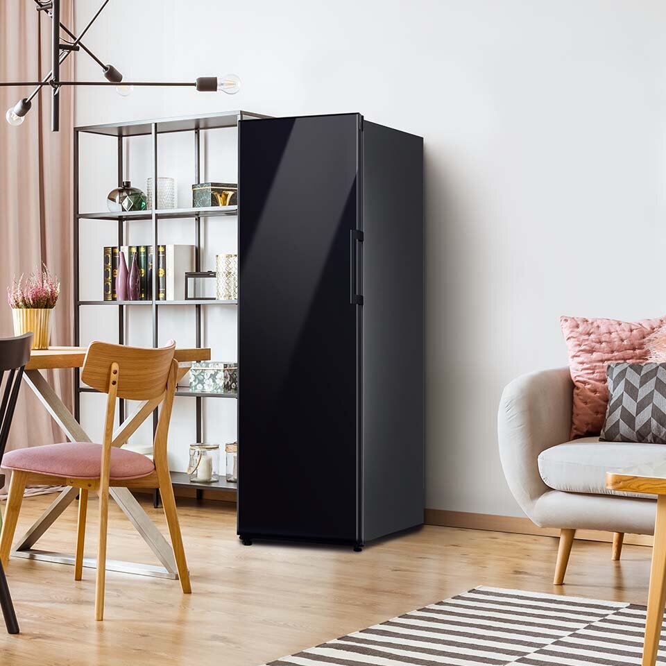 Model Samsung BESPOKE w kolorze głębokiej czerni został przedstawiony na zdjęciu jasnego pomieszczenia dziennego. Urządzenie umieszczone jest zaraz obok minimalistycznego regału. Model Samsung BESPOKE w kolorze głębokiej czerni został przedstawiony na zdjęciu jasnego pomieszczenia dziennego. Urządzenie umieszczone jest zaraz obok minimalistycznego regału.