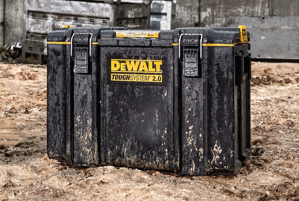 Skrzynka narzędziowa DEWALT DWST83342-1 plac budowy skrzynka ustawiona na piasku w tle betonowe konstrukcje porządek transport mobilność przechowywanie