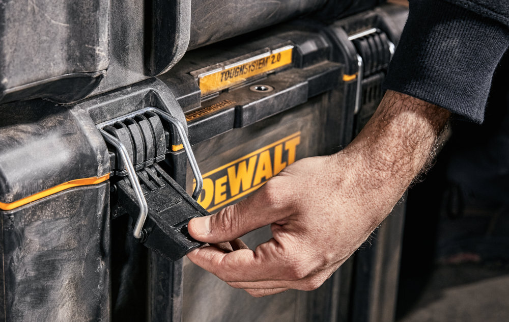 Skrzynka narzędziowa DEWALT DWST83342-1 zbliżenie na zamek osoba trzyma zamek w dłoni dwuczęściowe solidne metalowe zamki bezpieczne przechowywanie narzędzi i akcesoriów ochrona przed przypadkowym otwarciem podczas przenoszenia trwałość całej skrzynki