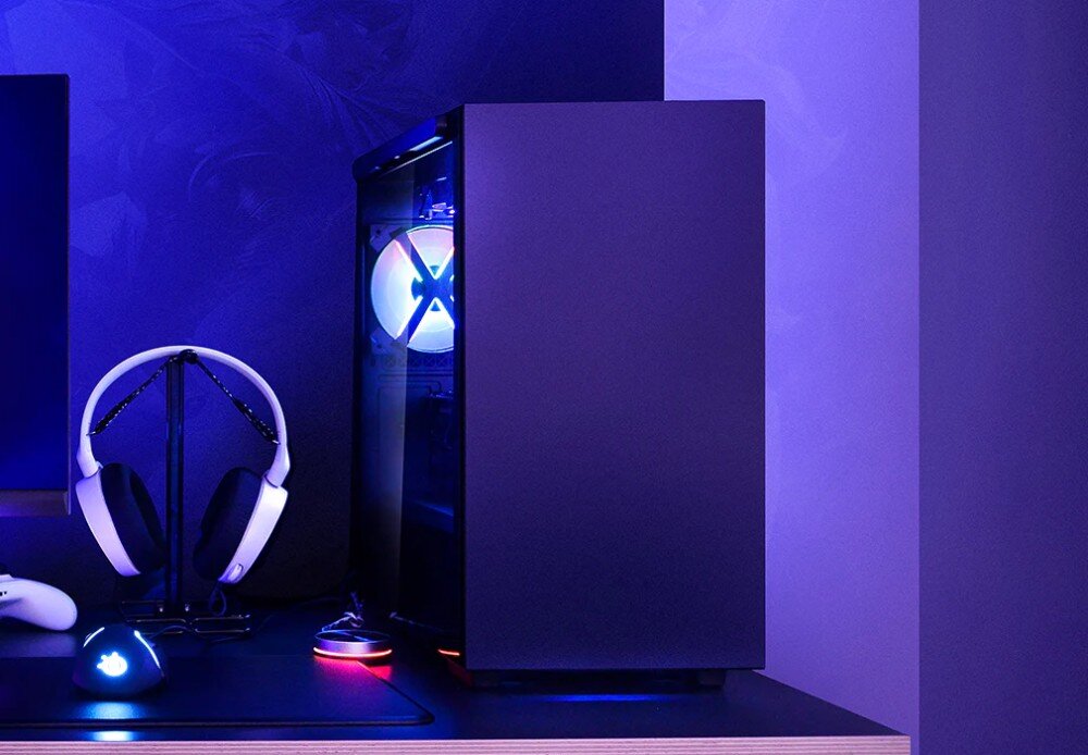Obudowa DEEPCOOL Macube 110 Obudowa komputera stacjonarnego z przeszklonym bokiem i wentylatorami z podświetleniem RGB, na biurku obok stojaka ze słuchawkami i myszki podświetlonych na niebiesko