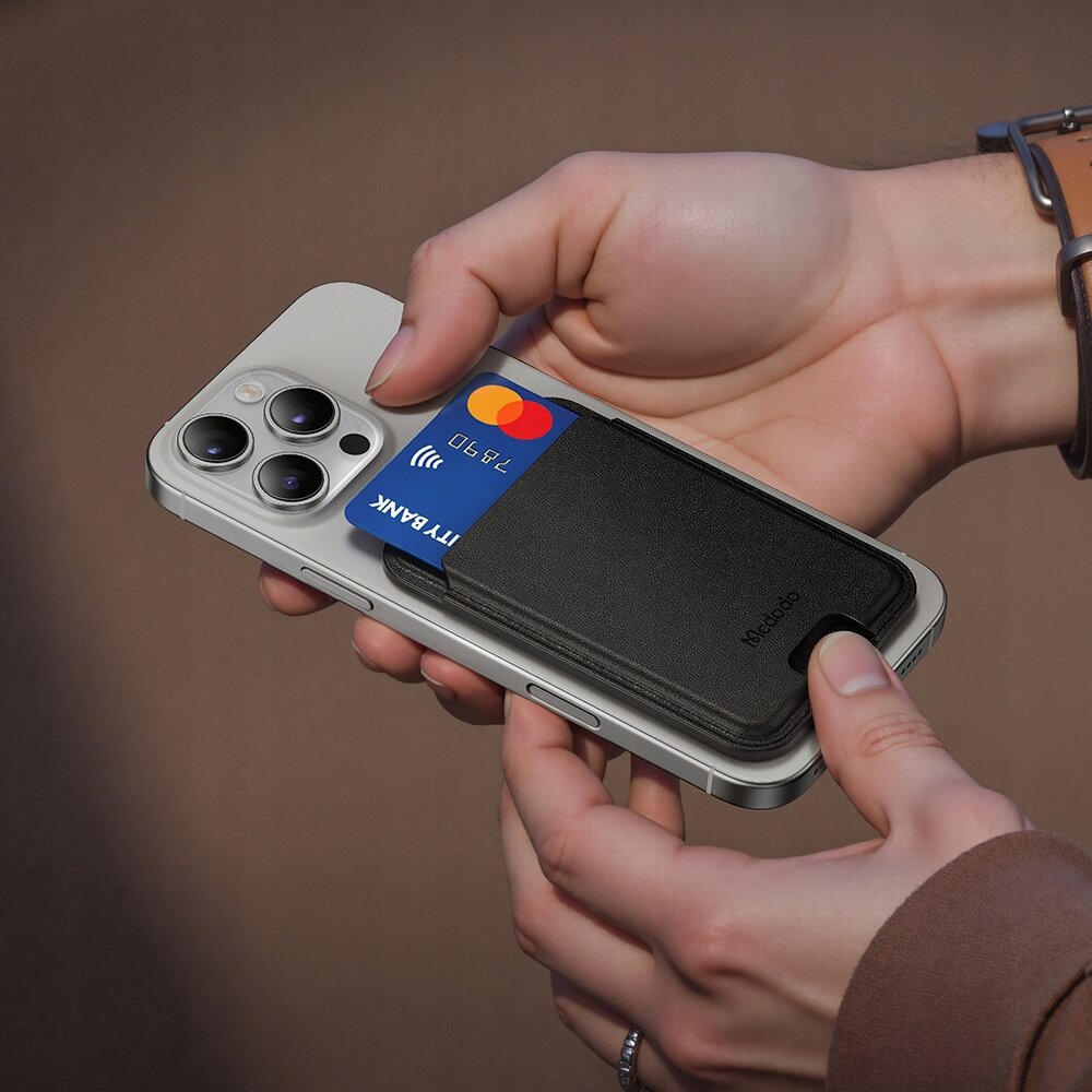 Osoba trzyma telefon z przymocowanym czarnym etui na karty kredytowe marki Mcdodo, w którym znajduje się karta płatnicza z widocznym napisem \'CITY BANK\'.