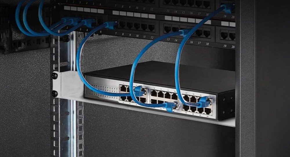 Półka EXTRALINK EX.12745 Urządzenie sieciowe z podłączonymi niebieskimi kablami ethernet leży na czarnej metalowej półce zamontowanej wewnątrz szafy rack
