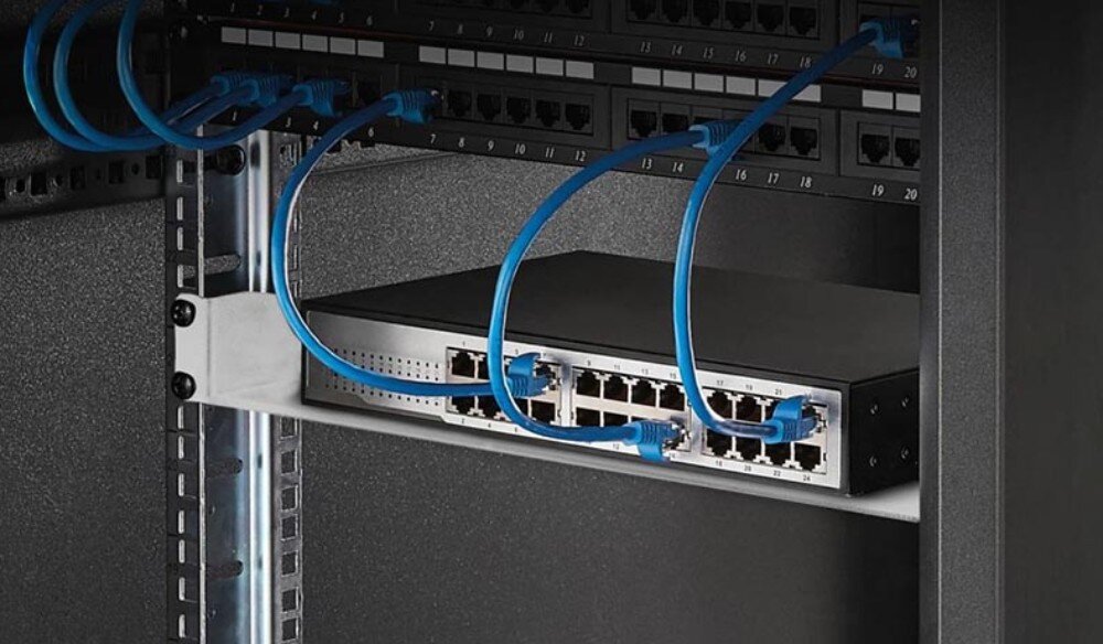 Półka EXTRALINK EX.12745 Urządzenie sieciowe z podłączonymi niebieskimi kablami ethernet leży na czarnej metalowej półce zamontowanej wewnątrz szafy rack