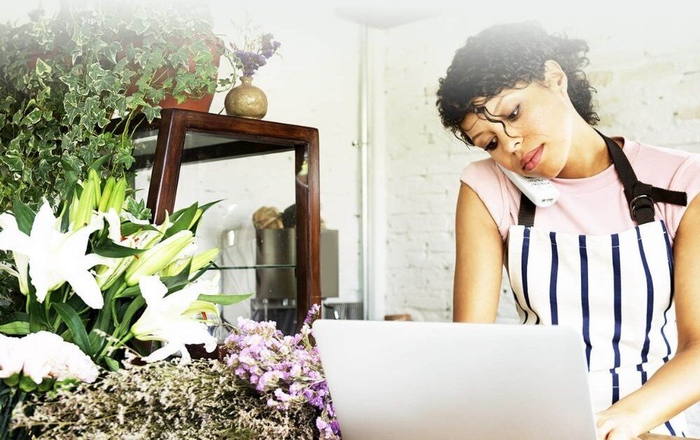 Router TENDA 4G06 Kobieta w kwiaciarni przy laptopie rozmawia przez telefon