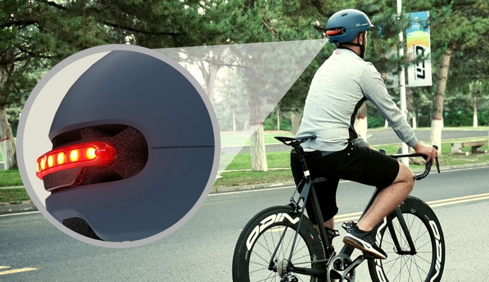 Kask LIVALL C20 Niebieski (rozmiar M) miasto osoba jedzie na rowerze po drodze obok zdjęcie w kółeczku ze zbliżeniem na diody wbudowane światło STOP z czujnikiem G-sensor automatycznie sygnalizuje hamowanie zwiększa bezpieczeństwo w ruchu miejskim