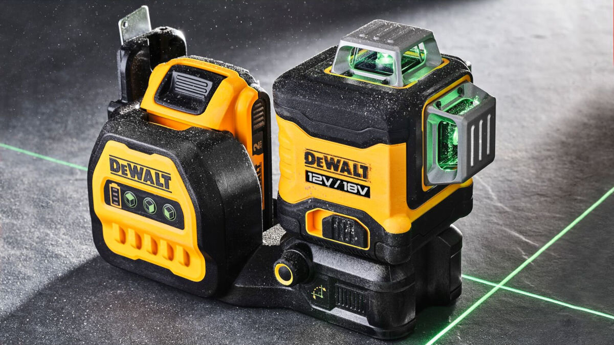 Laser krzyżowy DEWALT DCE089NG18, pomieszczenia, linia, całkowita, pozioma, laser stoi na podłodze frontem prawo skos, w tle wiązki lasera