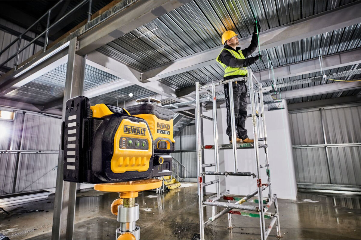 Laser DEWALT DCE089D1G18, impulsowy, projektuje, zasięg, detektor, mężczyzna na rusztowaniu w tle, na pierwszym planie laser zamontowany do stojaka