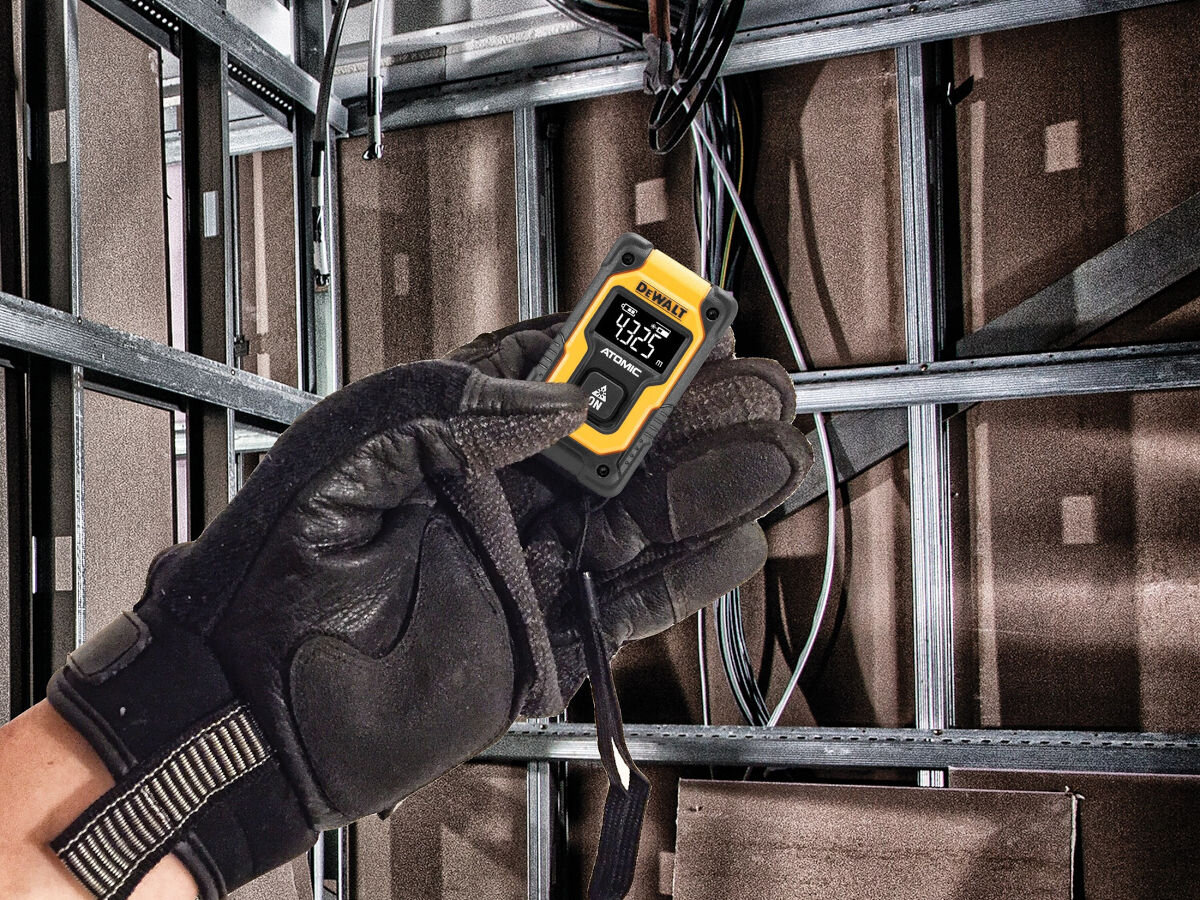 Dalmierz laserowy DEWALT DW055PL 16m, mierzenie, odległość, budowa, mierzenie, dłoń w rękawicy roboczej trzyma dalmierz