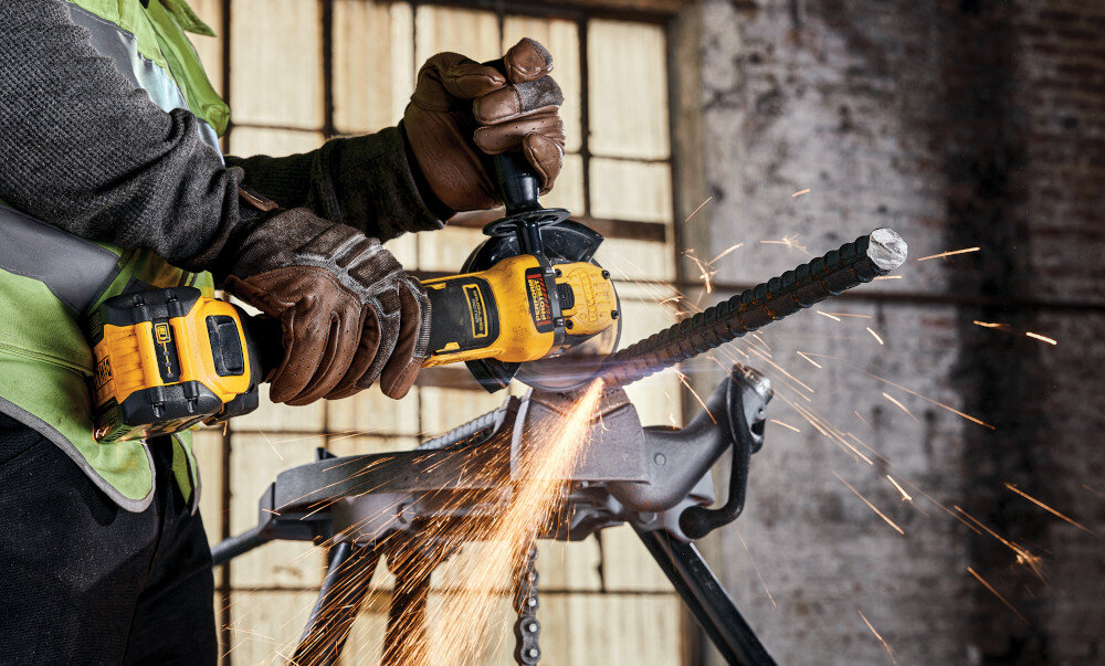 Szlifierka kątowa DEWALT DCG409NT osoba używa szlifierki tnąc metalową rurkę do cięcia i szlifowania różnorodnych materiałów zasilanie akumulatorowe do pracy w warsztacie i na placu budowy pełna mobilność swoboda ruchu