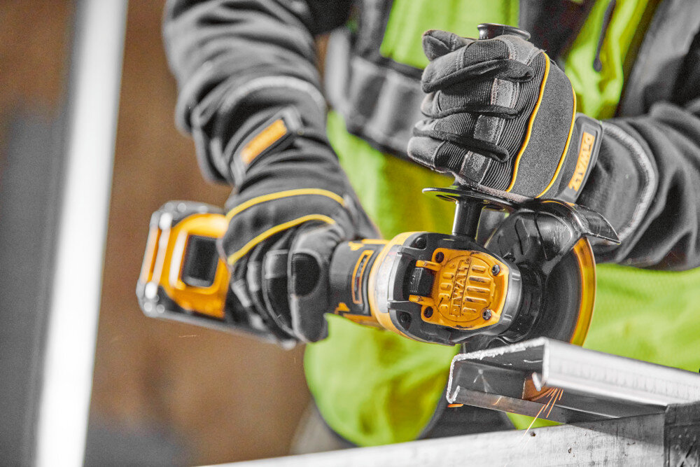 Szlifierka kątowa DEWALT DCG409NT osoba używa szlifierki tnie metalowy element funkcja Anti-KickBack element elektroniczny hamulec ogranicza ryzyko przypadkowych urazów wbudowane sprzęgło elektroniczne system Anti-Rotation E-CLUTCH