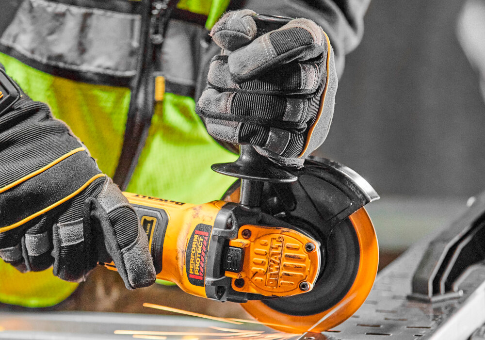 Szlifierka kątowa DEWALT DCG409NT osoba używa szlifierki tnie metalowy element suwakowy włącznik z blokadą antypoślizgowa dwukomponentowa obudowa stabilny chwyt dwupozycyjne mocowanie uchwytu bocznego indywidualne dopasowanie do stylu pracy i dominującej ręki