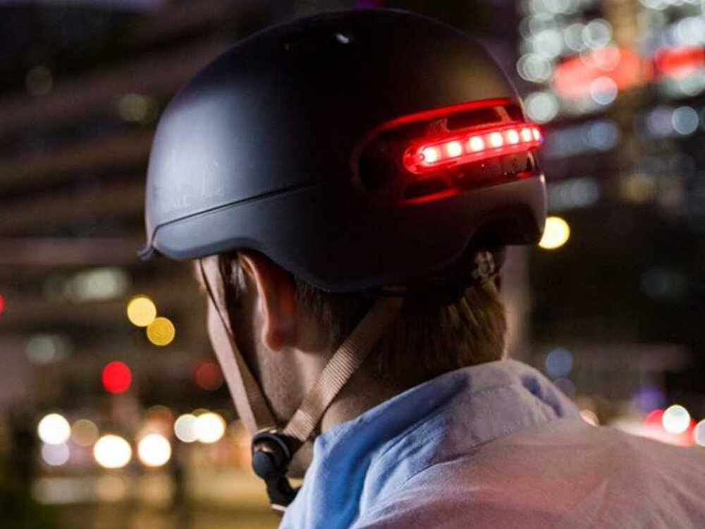 Kask LIVALL C20 Czarny (rozmiar L) miasto osoba w kasku widoczna od tyłu patrzy na światła miasta wbudowane światło STOP z czujnikiem G-sensor automatycznie sygnalizuje hamowanie zwiększa bezpieczeństwo w ruchu miejskim