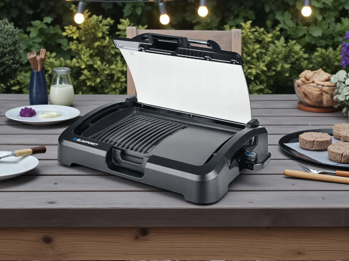 Grill elektryczny BLAUPUNKT GRT801, gotowanie, grillowanie, ogród, jedzenie, grill stoi na blacie stołu frontem prawo skos w ogrodzie
