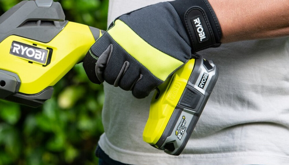 Nożyce do żywopłotu RYOBI RY18HT55A-0 ogród osoba trzyma nożyce w dłoniach zbliżenie na akumulator akumulatorowe pracuje na napięciu 18 V kompatybilne z platformą akumulatorową RYOBI ONE+ zasilanie wielu narzędzi jednym typem akumulatora szybciej przygotować się do pracy sprawniej zarządzać energią ograniczyć liczbę ładowarek niższe koszty eksploatacji większą wygodę